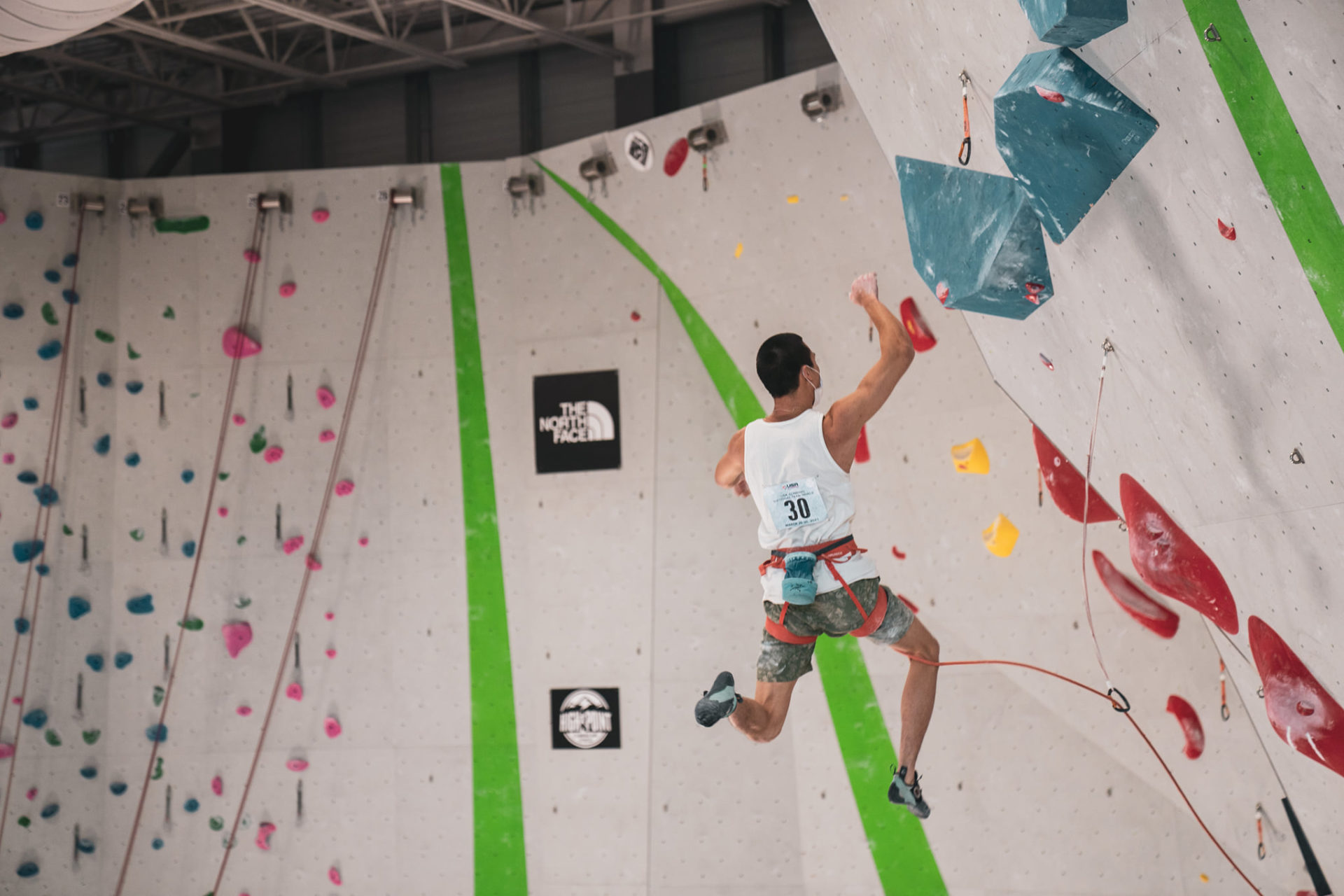 #30 Male climbing competitor mid jump on climbing wall